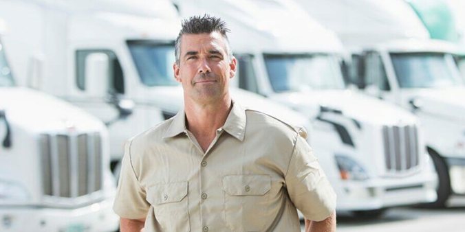 An owner-operator standing in front of a row of white trucks
